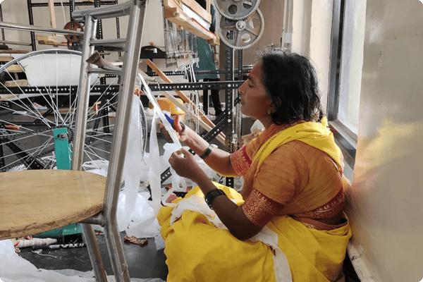 Artisan weaving upcycled plastic packaging materials into fabric on a handloom
