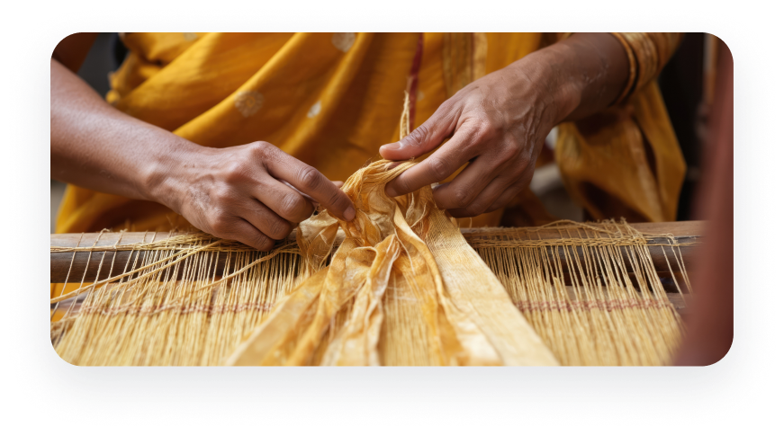 Hands guiding threads on a traditional handloom weaving a patterned textile
