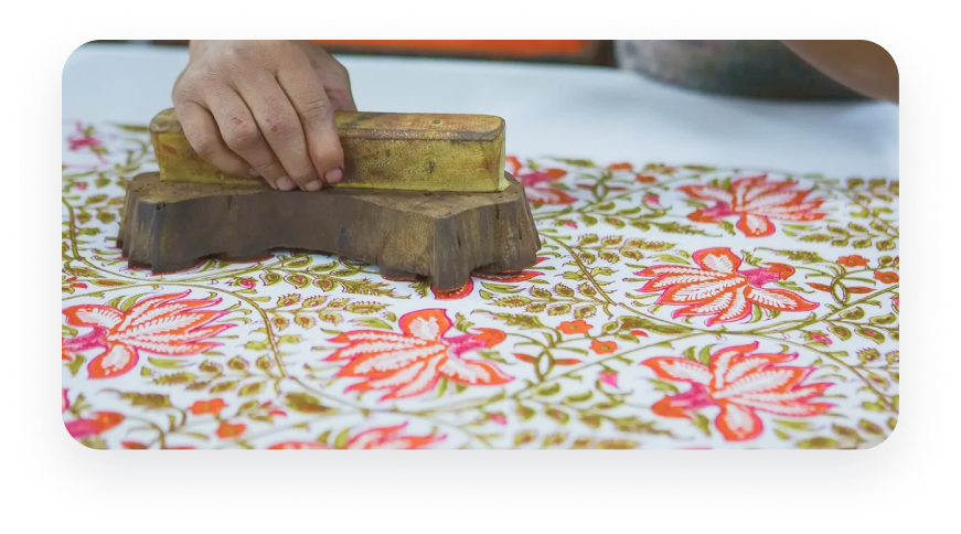 Hand pressing a carved wooden block onto fabric for traditional block printing